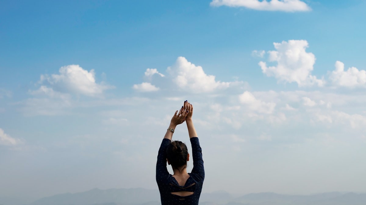 Woman raises hands towards the sky.